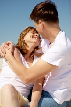 Portrait of amorous couple embracing against blue sky at summer