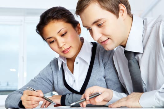 Successful colleagues working with papers in office