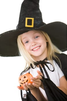 Portrait of girl in witch costume and small pumpkin in hands looking at camera