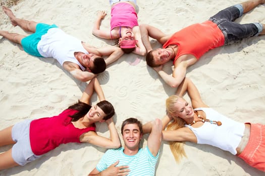 Six friends having rest on sandy beach