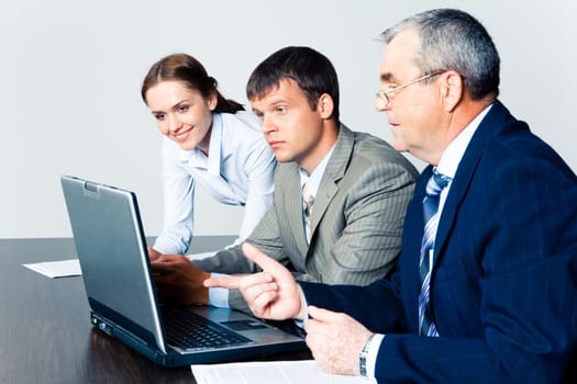Image of confident boss explaining some computer work to coworkers
