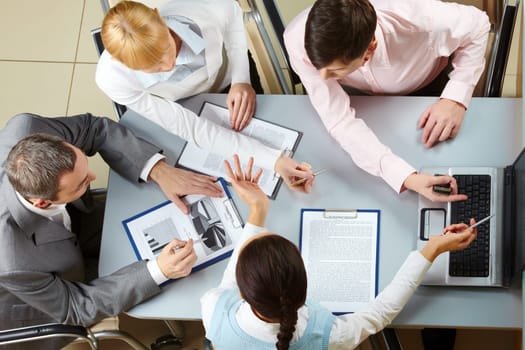 Above view of four business partners interacting at meeting