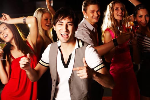 Portrait of energetic male dancing on background of happy friends