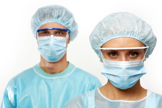 Two young surgeons in masks isolated on white
