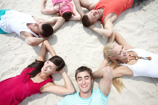 Six friends lying on sand in circle