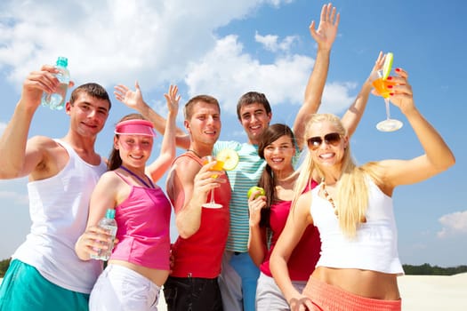 Six friends dancing on beach with cocktails