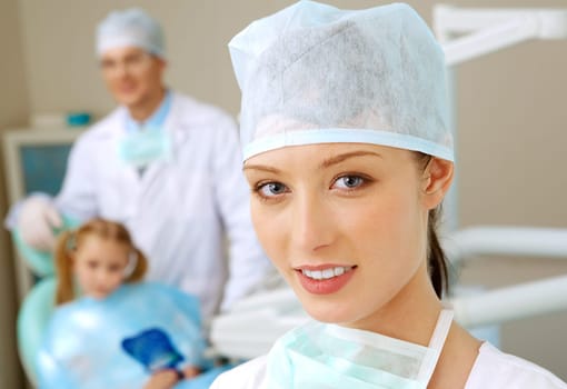 Portrait of young professional looking at camera on background of her colleague and patient