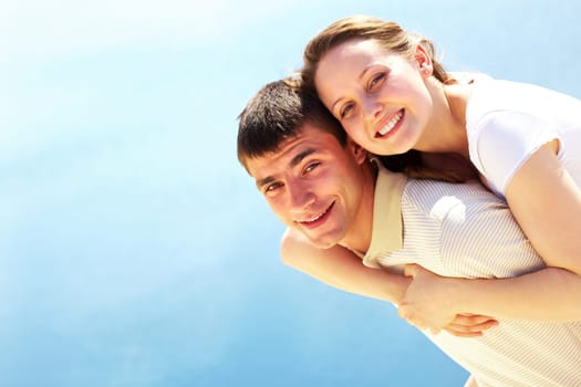 Photo of happy man giving piggyback to his girlfriend and both looking at camera