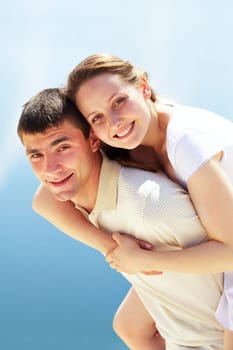 Photo of happy man giving piggyback to his girlfriend and having fun