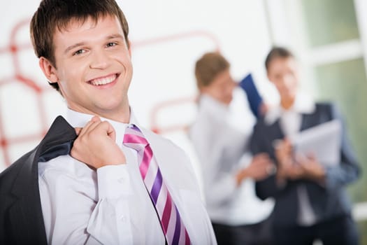 Satisfied smiling businessman standing on the background of business women