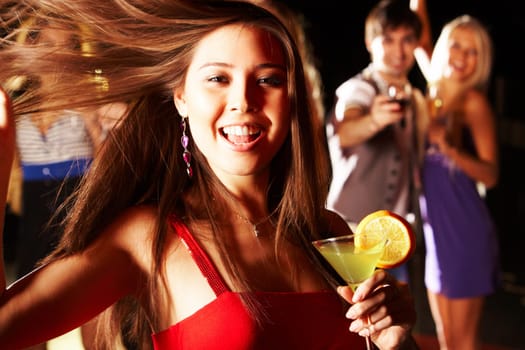 Portrait of cheerful girl with cocktail in hand laughing