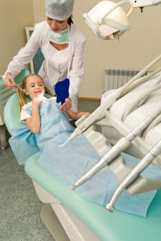 Dental inspection and treatment instruments with dentist and her patient at background