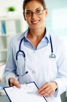 Portrait of confident female doctor with clipboard looking at camera