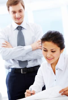 Portrait of pretty businesswoman reading document with her boss at background