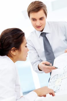 Smart woman looking at paper being pointed at by foreman in office