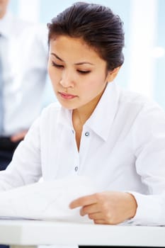 Portrait of serious businesswoman reading document in office