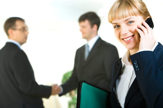 Portrait of business woman calling on the phone on the background of people shaking hands