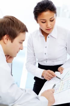Smart businesswoman pointing at paper and looking at it during discussion in office