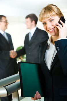 Photo of attractive employee speaking on the mobile in a working environment