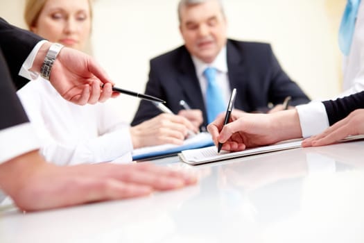 Close-up of business partners hands during planning in working environment