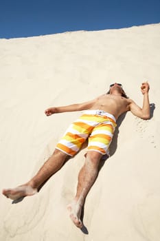 Happy guy lying on sandy beach and relaxing