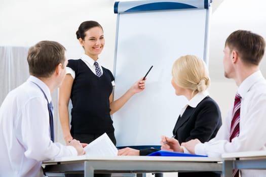 Photo of successful female standing by whiteboard while explaining her idea to colleagues