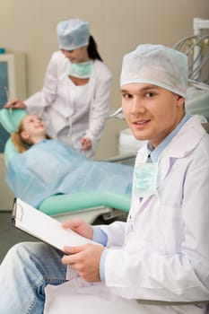 Image of sitting dentist with papers in hand looking at camera