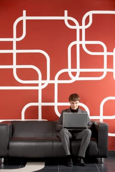 A businessman working on computer by the wall