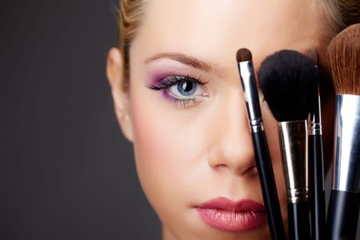 Close-up of young gorgeous female with brushes looking at camera