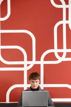 A businessman sitting by the wall concentrated on his laptop