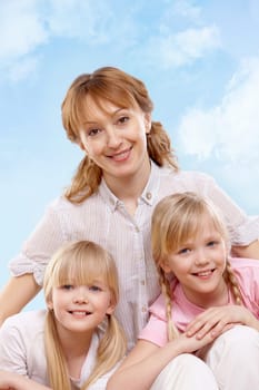 A young family of woman and twin sisters looking at camera