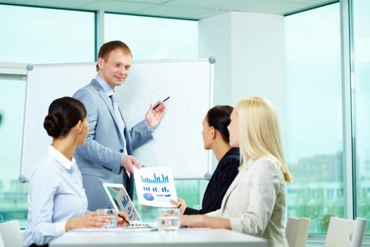 A business man showing something on a whiteboard to his colleagues