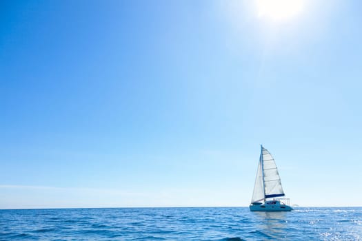 Lone sailboat in the open sea with bright sunny skies