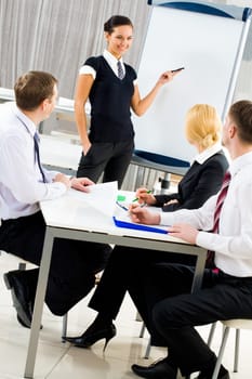 Smart and confident employee pointing at whiteboard while presenting her ideas