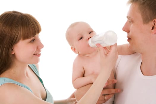 Image of baby drinking milk from bottle in female hand while being held by father