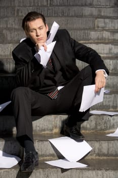 Portrait of stressed specialist thinking about crisis while sitting on staircase