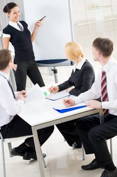 Image of several listeners looking attentively at young consultant pointing at board