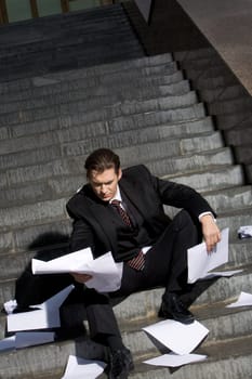 Image of frustrated man sitting with papers in hands and reading them