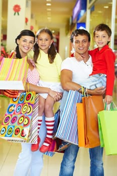 Portrait of couple with two children and shopping bags looking at camera and smiling