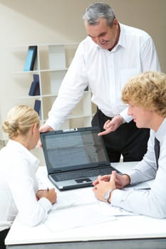 Image of senior boss presenting computer work to young partners