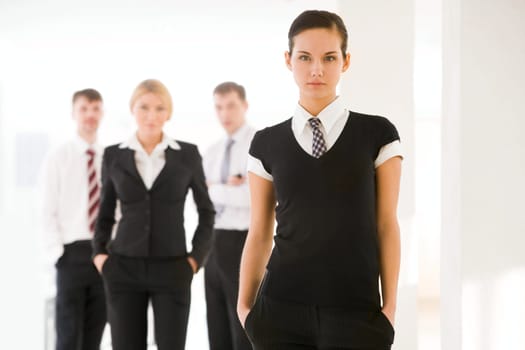Portrait of attractive business lady looking at camera on background of employees