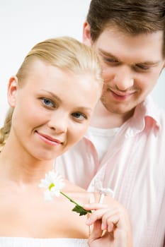 Lovely female holding white flower with amorous guy at background