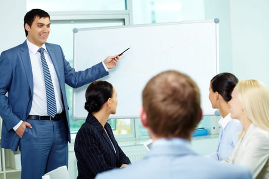 A business man showing something on a whiteboard to his colleagues