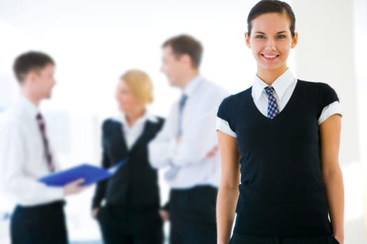 Portrait of attractive business lady looking at camera with smile on background of working people