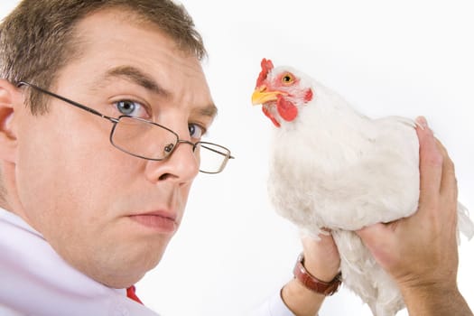 Photo of serious man holding white hen in hands and looking at camera