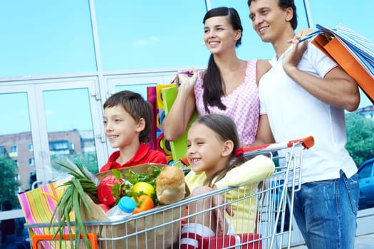 Couple with shopping bags pushing cart with two children