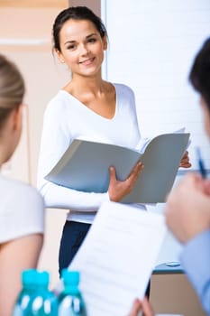 Portrait of successful business woman holding a folder and looking at her colleagues at meeting