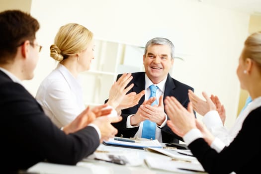 Image of senior leader surrounded by his colleagues applauding to him