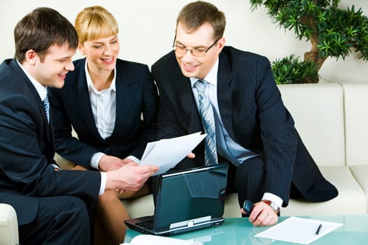 Two businessmen and businesswoman looking at document at meeting in the room