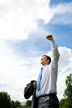 Portrait of happy man standing outside in rural environment with his arm raised upwards